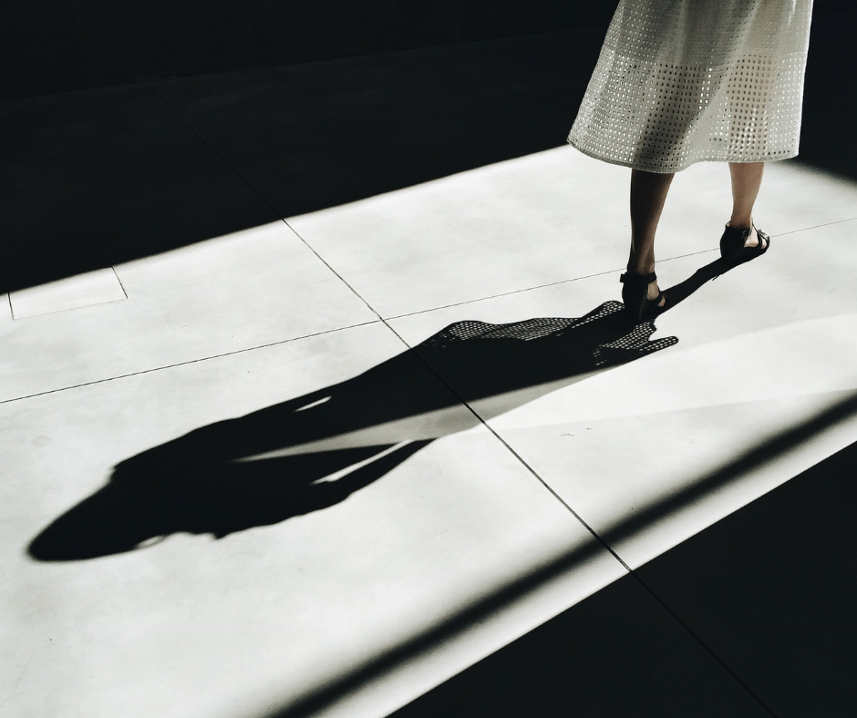 A woman walking in dark, you can see her shadow on the floor