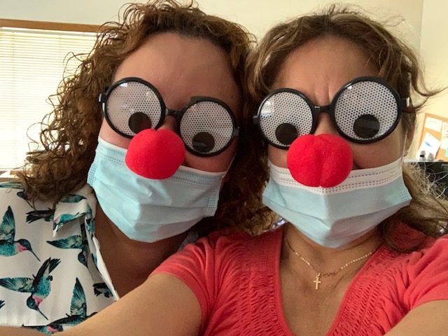 Two participants wearing silly eye glasses and a clown nose