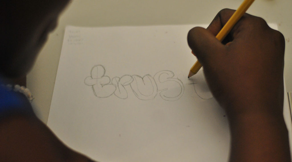 A person writing "trust" on a piece of paper